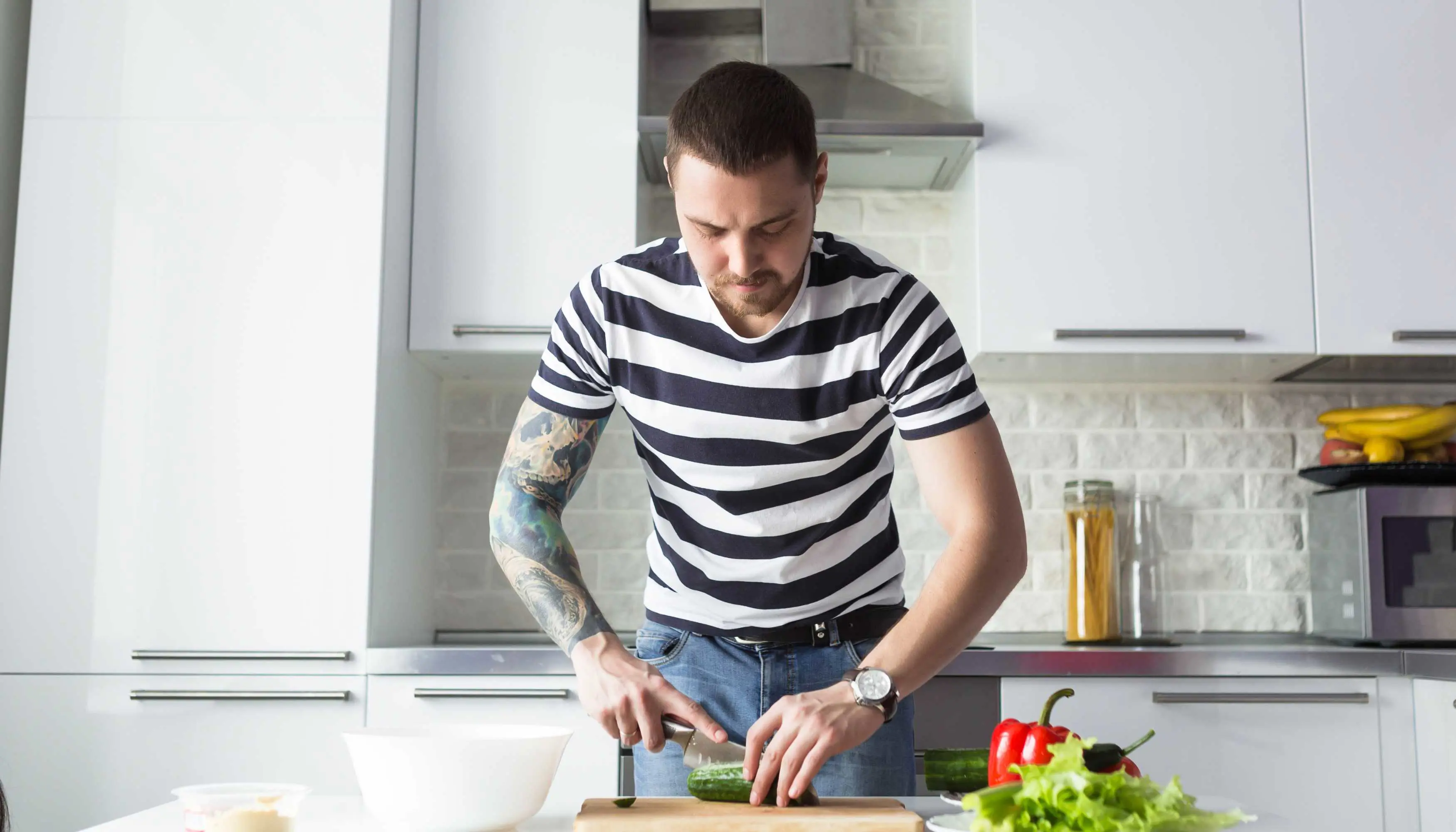 man chopping cucumber in kitchen