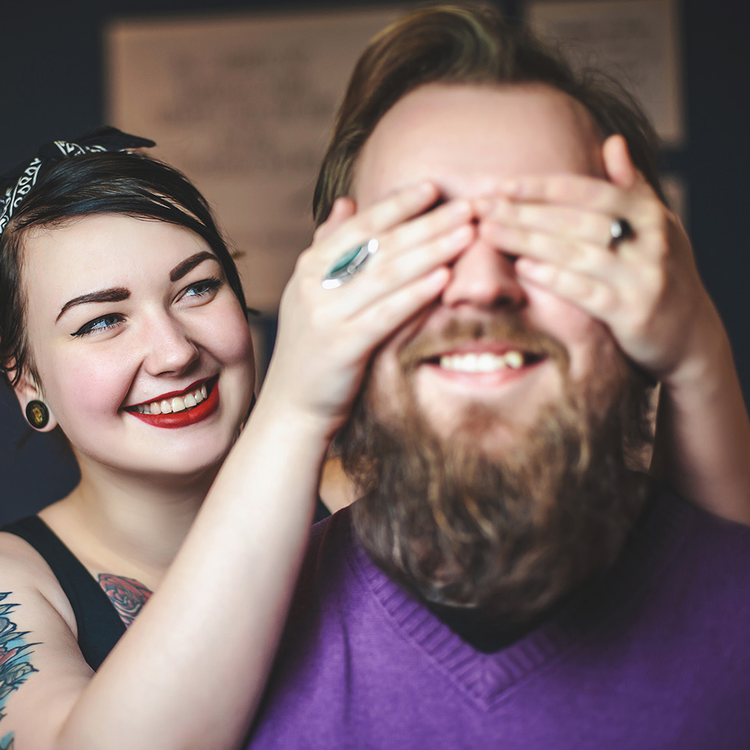 alternative couple holding hands over their eyes